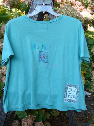 Barclay Crop Top with Oversized Sleeves and Rose Medallion Design on Aqua Background.