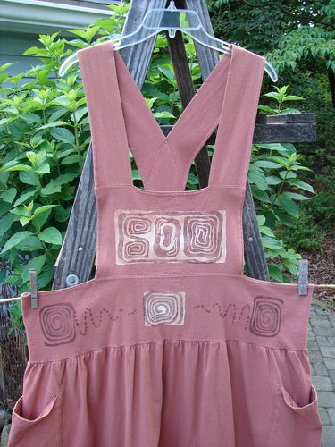 1995 Overall Jumper Stone Path Russet OSFA hanging on a clothesline, showcasing its creatively cut bib, full gathered skirt, crisscross back straps, and oversized side pockets.