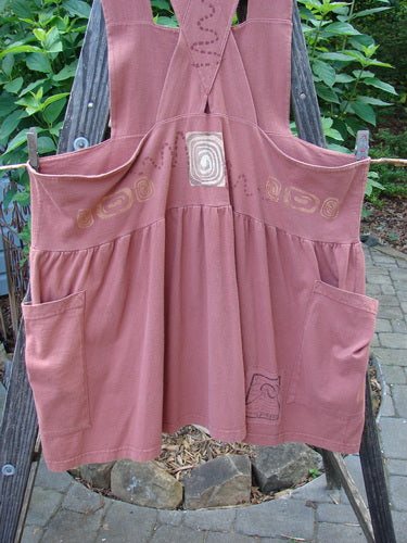 1995 Overall Jumper Stone Path Russet OSFA hanging on a clothesline, featuring a creatively cut overall bib, crisscross back straps, oversized side pockets, and a full gathered skirt.