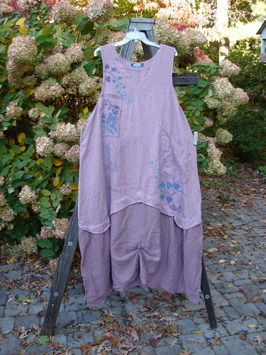 Barclay PMU Linen Explorer Jumper Pansy Lavender Size 2: A medium weight linen dress on a rack with a scoop neckline, full bodice overlay, and billowy lower sweep. Features include a generous upper pocket and a single rippie front hem lift.