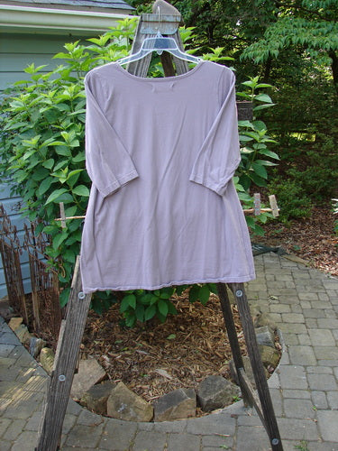 Barclay Three Quarter Sleeved Tee Play Dress Up Lilac Size 1 displayed on a clothes rack, showcasing its thinner flattened neckline and detailed design elements.