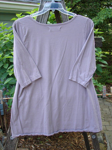 Barclay Three Quarter Sleeved Tee Play Dress Up Lilac Size 1 on a clothes rack, showcasing its delicate neckline and three-quarter sleeves, crafted from mid-weight organic cotton.