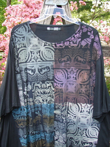 Barclay Art Tunic Tee Field Friends True Black OSFA hangs outdoors, showcasing its patchwork of geometric and floral motifs in a loose, long-sleeved design with a rounded neckline and varied hemline.
