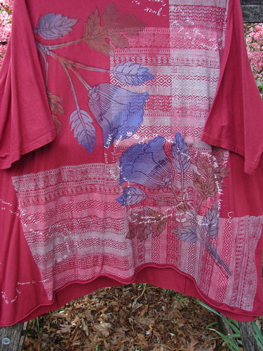 Barclay Art Tunic Tee Trailing Floral Deep Ruby OSFA drapes over a wooden railing, showcasing its loose fit, three-quarter sleeves, and trailing floral design, embodying Bluefishfinder.com's vintage, expressive style.