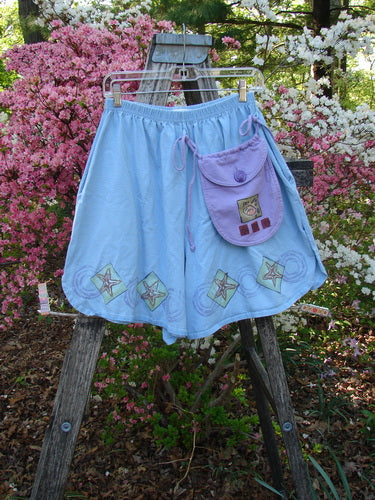 1997 Collector's Short Starfish Atlantis Size 1 displayed in a garden setting, featuring decorative star patches, a removable lavender pouch, and a full elastic waistline, exuding vintage Blue Fish Clothing charm.