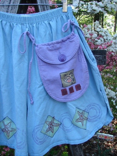 1997 Collector's Short Starfish Atlantis Size 1: A knee-length, light blue skirt with lavender pocket, elastic waistband, starfish motifs, and side draw-strings. Perfect for beach shelling, showcasing vintage Blue Fish creativity.