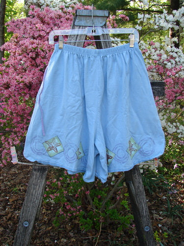 1997 Collector's Short Starfish Atlantis Size 1: Light-blue cotton shorts with painted starfish accents, elastic waist, and inseam pockets, displayed outdoors on a hanger with floral backdrop. Perfect for beach shelling.
