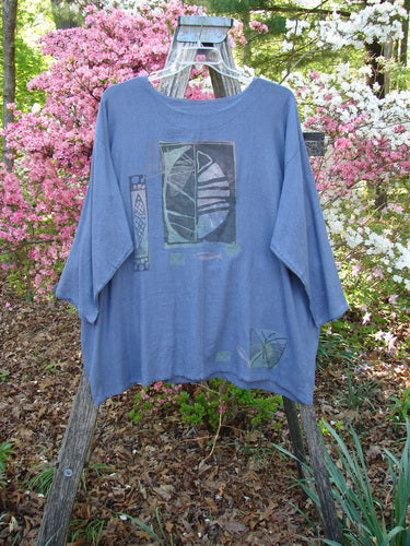1995 Silk Noile Long Sleeved Top Leaf Fish Butterfly Dusk OSFA draped on a wooden ladder, features abstract leaf and geometric designs. Surrounded by flowering shrubs, embodying Bluefishfinder.com's vintage, expressive style.