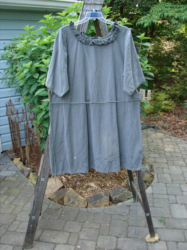 Barclay Linen Duet Sunrise Dress Soft Floral Army Size 1 hanging on a clothesline, showcasing its unique cotton linen fabric, curly neckline, vertical pleats, and painted pockets.