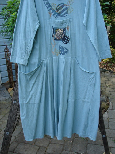 1995 Farmer Jen Dress Fish Atom Dinette Green Size 1 displayed on a wooden ladder, showcasing its rounded neckline, longer sleeves, multiple pockets, and signature Blue Fish Patch.