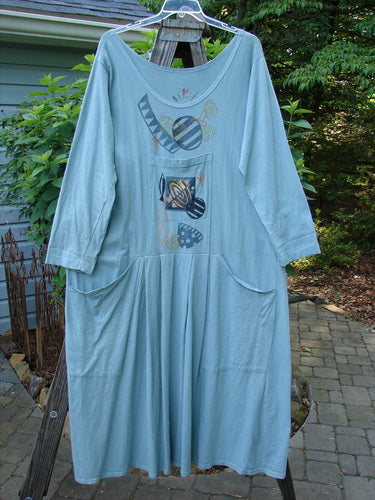 1995 Farmer Jen Dress Fish Atom Dinette Green Size 1 on a clothes rack, showcasing its longer cozy sleeves, A-line shape, multiple pockets, and signature Blue Fish patch.