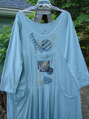 1995 Farmer Jen Dress Fish Atom Dinette Green Size 1, featuring long sleeves, a deeper rounded neckline, multiple pockets, and unique atom-themed paint, displayed hanging on a clothesline.