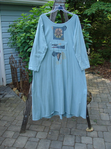 1995 Farmer Jen Dress Fish Atom Dinette Green Size 1 hanging on a clothesline, showcasing its long sleeves, wider neckline, and multiple front pockets, emblematic of vintage Blue Fish Clothing.