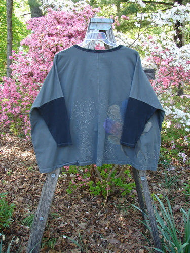 Barclay Cotton Lycra Rib Colors Contrast Sweatshirt Peony Night Grey OSFA draped on a ladder, showcasing a boxy shape, contrasting navy sleeves, and peony-themed paint details, amidst blooming azalea bushes.