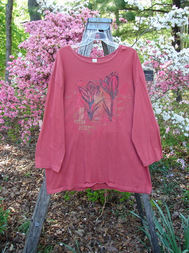 Barclay Long Sleeved Studio Tee Double Crocus Harvest Size 2 displayed on a wooden ladder, featuring long sleeves and a flower graphic, set against blooming pink and white shrubs.