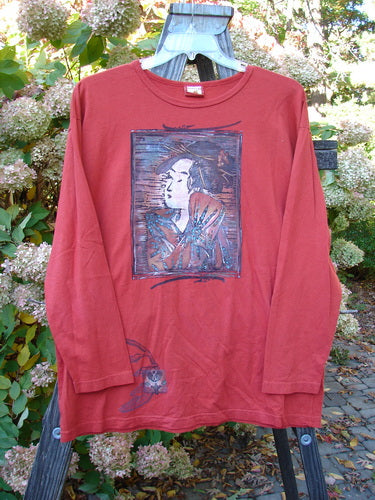 A red shirt with a picture of a Geisha Gal theme paint on the front. Long cozy sleeves and a wide slightly longer shape. Organic cotton. Size 1.