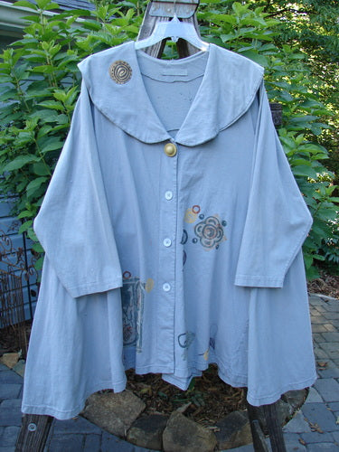 1994 PMU Wanderer's Jacket English Garden Solstice Blue Size 2 displayed on a hanger, showcasing a wide shawl collar, sectional side inserts, and a varying hemline.