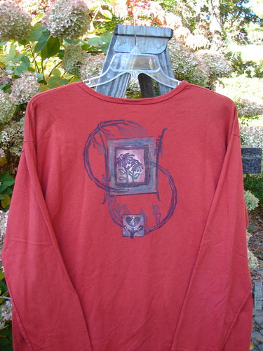 A red shirt with a picture on it featuring a Geisha Gal theme paint. The Barclay Long Sleeved Tee is from the Fall Collection in Geisha's Robe, made from Organic Cotton.