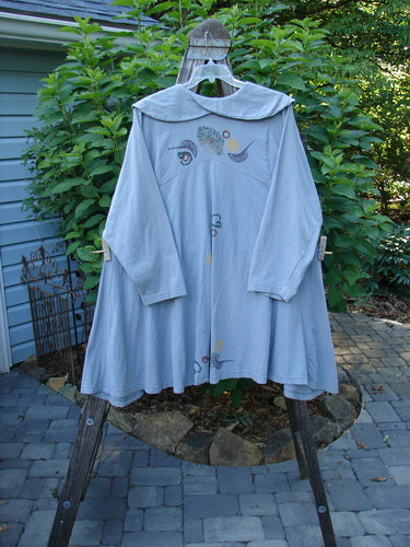 1994 PMU Wanderer's Jacket English Garden Solstice Blue Size 2 displayed on a wooden rack, showcasing its wide shawl collar, downward yoke, sectional side inserts, and unique top button.