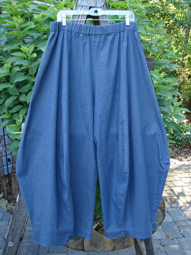 A pair of Barclay Light Weight Denim Crop 4 Square Pant Unpainted Indigo Size 2 hanging on a clothes rack, showcasing the unique 3D diamond cut from the knee down and billowy bottom.