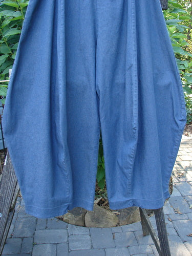 A pair of Barclay Light Weight Denim Crop 4 Square Pants Unpainted Indigo Size 2 on a metal rack, showcasing a unique 3D diamond drape from the knee down.