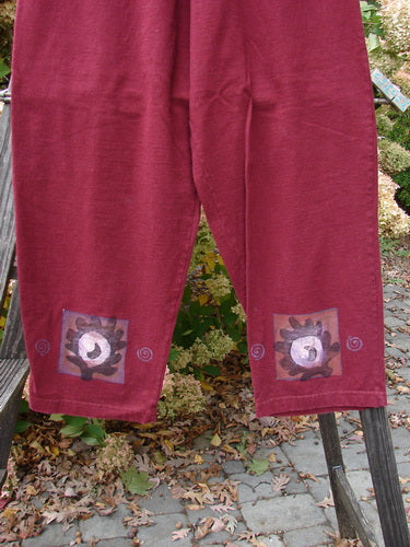 Image alt text: 1997 Holiday Simple Pant Balanced Atom Regalia Size 0: a pair of red pants with designs on them, made from organic cotton, featuring a full elastic waistband, deep side pockets, and a slightly straighter fall.