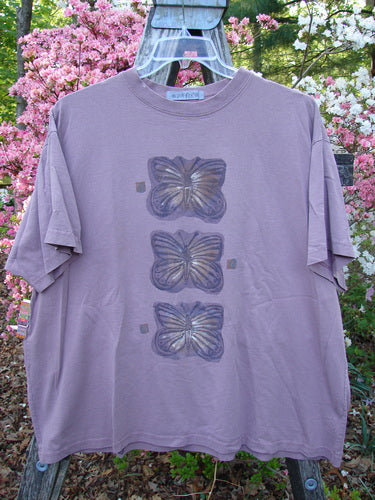1996 Short Sleeved Tee Triple Butterfly Petal Size 2 displayed on a hanger, features three vertically stacked butterfly motifs on a faded lavender-purple fabric, showcasing vintage charm and creative design.