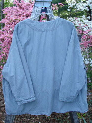 The 2000 Percal Overshirt Top Unpainted Eucalyptus Size 2 drapes elegantly on a metal stand, showcasing its loose, flowing silhouette and distinct drop waist seam with a soft V-shaped neckline.
