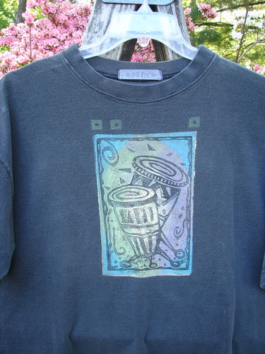 1996 Short Sleeved Tee Drummer Storm Size 1 features a pastel graphic of abstract drum shapes, confetti flecks, and swirling lines on a charcoal T-shirt outdoors, reflecting vintage Blue Fish creativity.