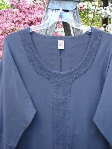 Barclay Cotton Lycra Celtic Moss Single Pocket Tunic Unpainted Grey Plum Size 1, featuring a textured trim and scooped neckline, displayed on a hanger against blooming trees.