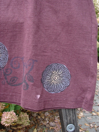 Image alt text: "1997 Short Sleeved Tee with Triple Leaf Stained Glass design on purple towel, made from organic cotton"