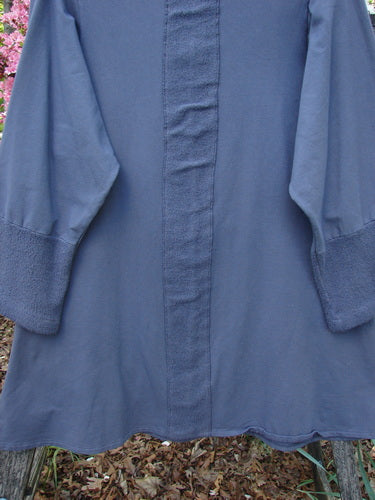 Barclay Cotton Lycra Celtic Moss Single Pocket Tunic Unpainted Grey Plum Size 1, featuring cuffed sleeves, an A-line shape, floppy side pocket, and Celtic Moss accents, hanging outdoors.