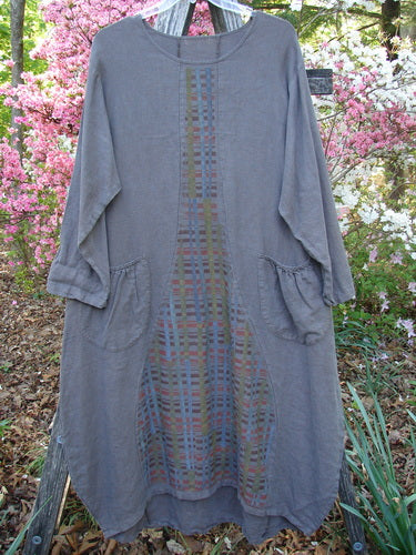 Barclay Linen Tea Ceremony Thostle Dress Cross Grid Dark Stone Size 1, featuring a long-sleeved, loose fit with multicolored grid stitching on a muted gray, heavier weight linen, displayed on a hanger.