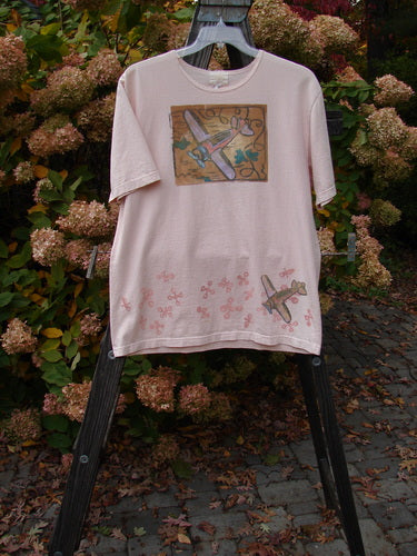2001 Short Sleeved Tee Airplane Pink Tile Size 0: A pink shirt with a picture of an airplane on it, made from organic cotton. Slightly thicker ribbed neckline, drop shoulders, and a slightly longer length. Perfect condition.