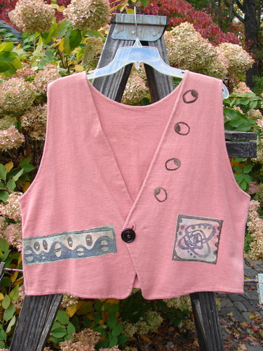 1995 Jazz Vest Greyhound Papaya Size 2: A pink vest with black buttons on a wooden stand. Contrasting front angled hemline, deep V neck, and single button closure. Features a greyhound theme paint.