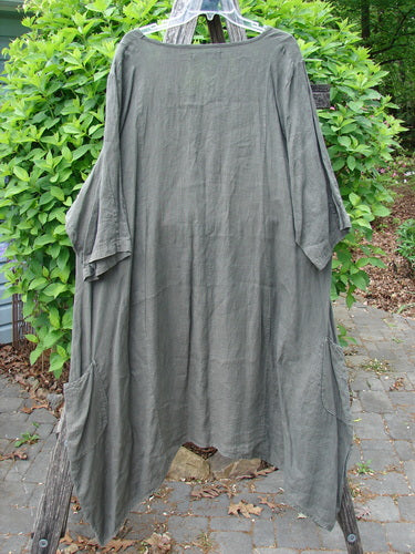 Barclay Linen Drop Pocket Bell Dress Unpainted Stick Size 2, showcasing wide sleeves and dual drop wrap side pockets. This oversized, A-line smock hangs against a leafy backdrop, emphasizing its artistic, vintage appeal.