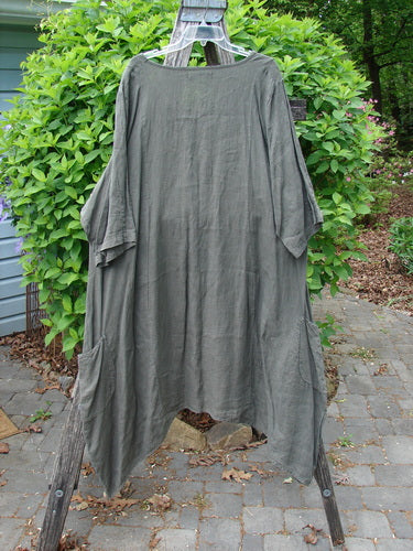Barclay Linen Drop Pocket Bell Dress Unpainted Stick Size 2: Oversized tunic-style dress with drapey mid-length sleeves, side pockets, and curved seams, hanging on a wooden ladder outdoors.