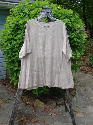 Barclay Lightweight Linen Tea Time Top Unpainted Rice Paper Size 2 on a hanger over a wooden stepladder, showcasing its loose, flowy A-line shape and rounded neckline amid a natural setting.