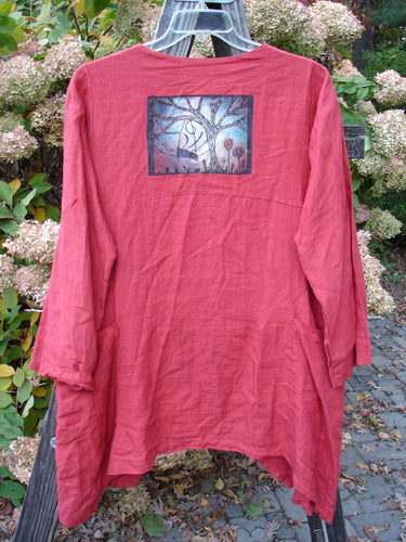 A red shirt with a picture on it, featuring a painting of a tree and a close-up of a plastic object.