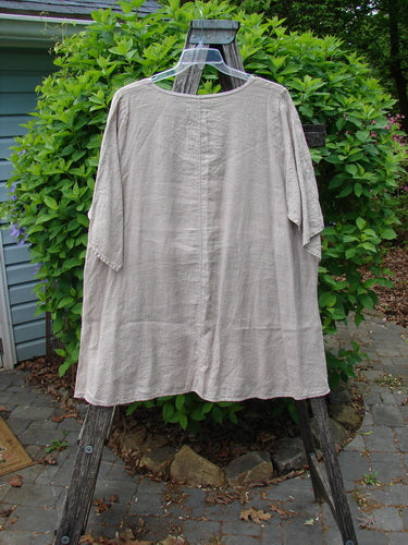 Barclay Lightweight Linen Tea Time Top Unpainted Rice Paper Size 2, displayed on a wooden ladder, features a loose fit, short sleeves, rounded neckline, and asymmetrical hem, embodying Bluefishfinder.com’s vintage-inspired style.