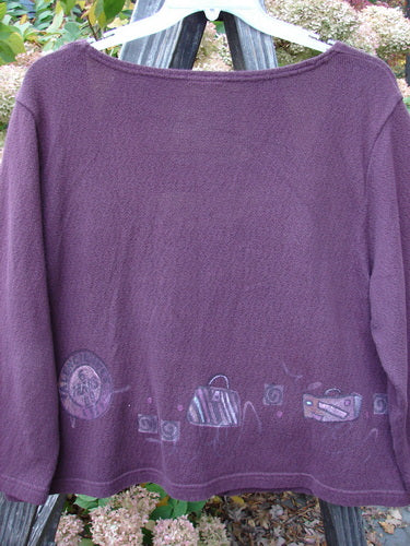 A close-up of a purple Barclay Textured Cotton Crop Box Sweater with travel-themed paint designs and cozy sleeves.
