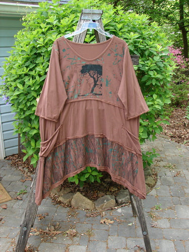 Barclay Raw Seam Vector Tunic Dress Single Tree Redwood Size 2 hanging on a wooden ladder. Features three-quarter sleeves, tree motif, tiered hem with stripe, and raw edges, embodying Bluefishfinder's vintage bohemian style.