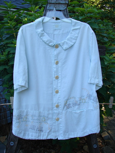 2000 Tencel Camp Shirt Airmail Shark Size 0, featuring a smaller Peter Pan collar, oversized contrasting buttons, front drop pocket, and full paneled sweep, displayed on a clothes rack.