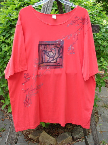 Barclay Short Sleeved Studio Tee Birdy Branch Pomegranate Size 3 features a warm red, loose-fit design with a stylized bird graphic and twig blossom motifs, hanging against lush greenery.