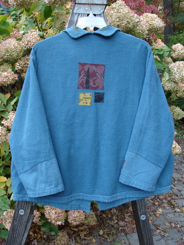 A Barclay Patched Frolic Jacket in Ocean Teal, featuring a patch and ribbed cord accents. Sweet roll over painted neckline, contrasting lower sleeves, and button placket. Unique buttons, oversized exterior pocket with a garden theme. Cozy and swings just great! Size 0.