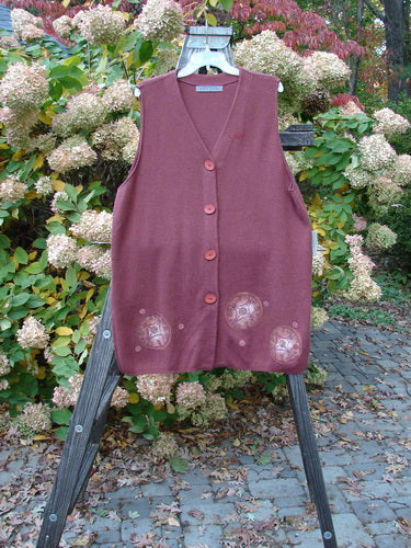 1997 Cashmere Archway Vest with Celtic Wheel design. A red vest with buttons on a rack. Close-up of a sweater. A purple vest with buttons.
