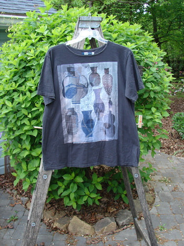 Barclay Fiona Straight Tee Modern Vase Storm Size 0, featuring grid-style guitar silhouettes in muted blues and grays, draped over a ladder with garden foliage in the background.