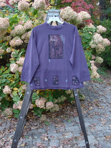 1997 Long Sleeved Tee Spirit Drum Ionic Size 1: A purple shirt on a wooden rack. Mid-weight cotton, wider neckline, cozy longer sleeves. Features Spirit Woman and Drum theme paint. Bust 50, waist 50, hips 50, length 28.