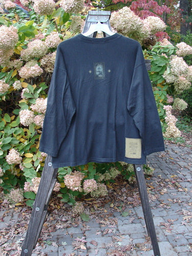 Image alt text: "1997 Long Sleeved Tee Stone Door Cast Iron Size 1: A long sleeved shirt on a rack with a wooden ladder and blanket underneath."