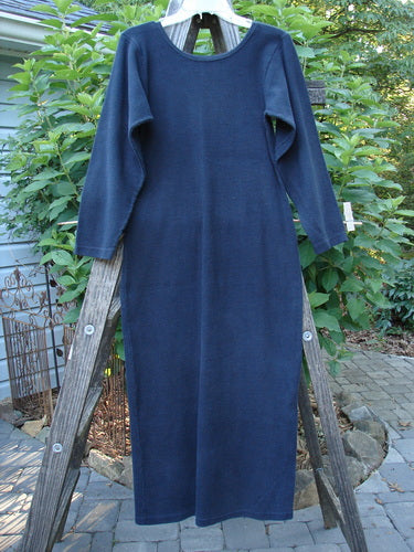 A 1991 Rib Thermal The Skinny Dress Unpainted Charcoal Altered OSFA hangs on a wooden ladder, showcasing its long sleeves, straight linear shape, and rounded neckline.